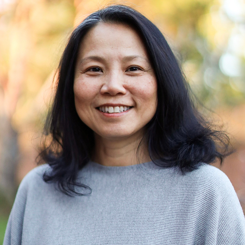 A woman in a grey sweater smiling.