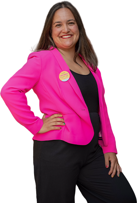 A woman in a pink blazer posing with her hand on her hip