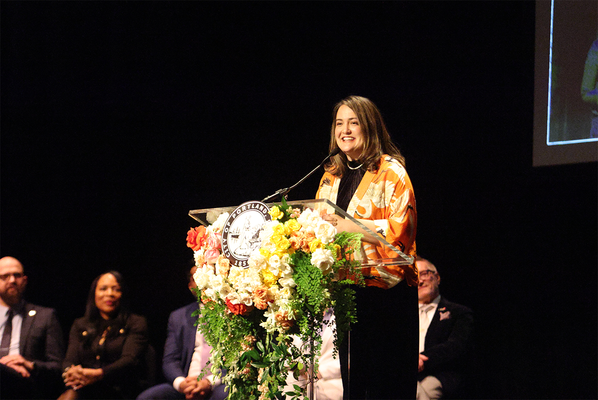 A woman standing behind a lectern with a City of Portland seal.